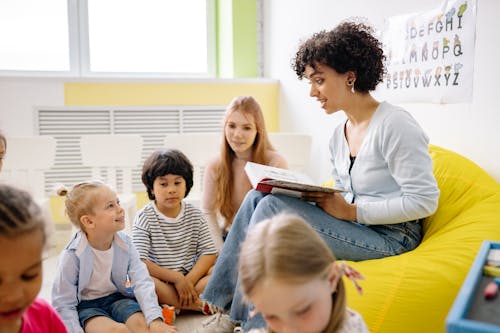 Free Teacher reading to preschool kids in a colorful classroom setting. Stock Photo